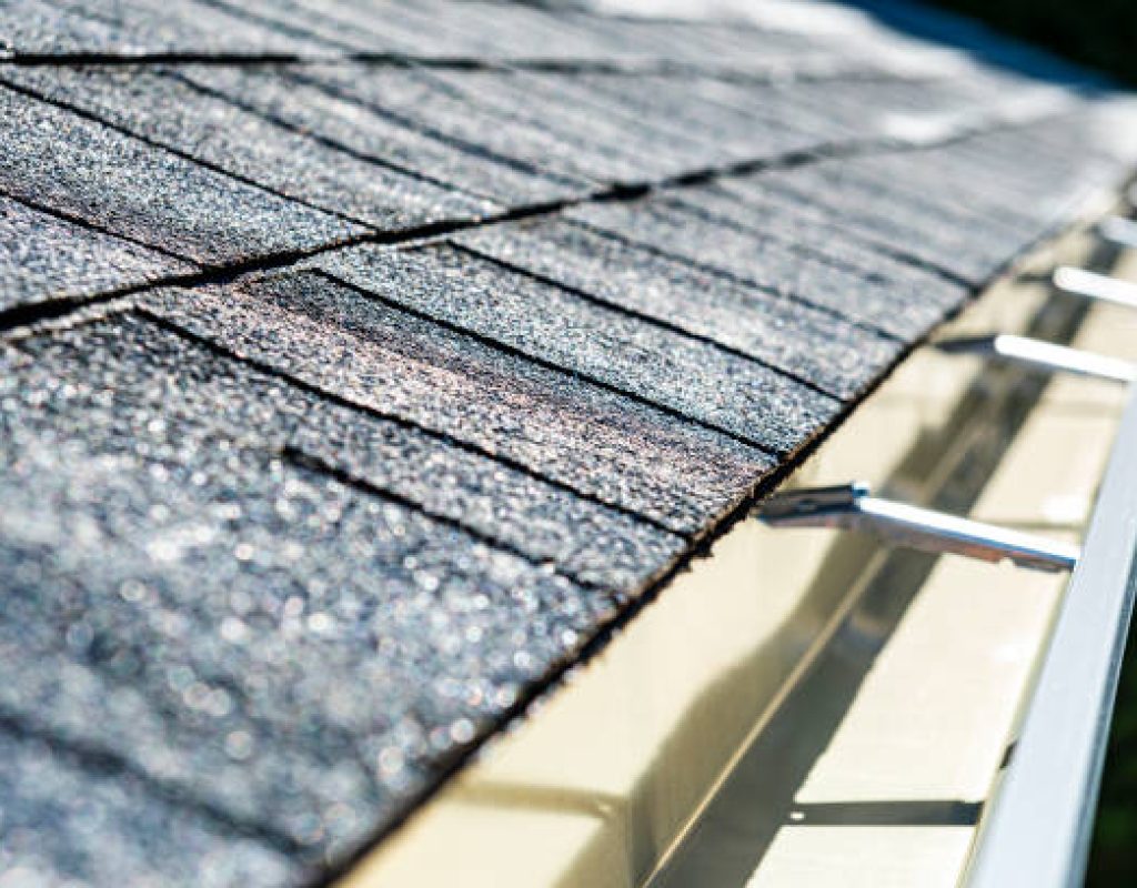 SLR Services Florida expert gutter installation service A close-up of a newly installed architectural shingle roof and seamless aluminum rain gutters on a residential home.