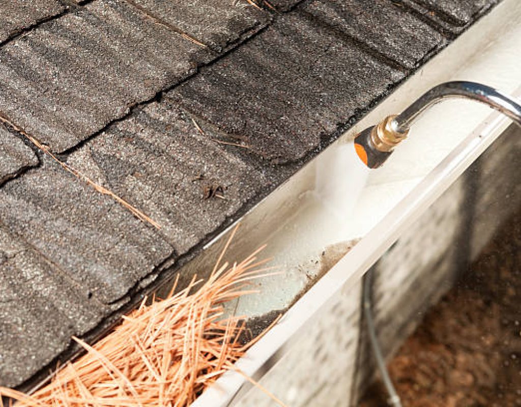 Professional gutter cleaner removing buildup to enhance drainage system performance.